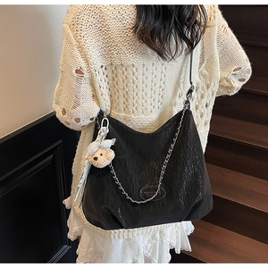 Detail of black Hobo bag with sparkling texture and cute bear charm worn by a model