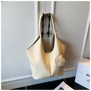 Detailed macro view of the cream lychee-grain leather texture on a slouchy tote bag