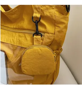 Detail of yellow nylon tote bag featuring a detachable small round pouch and metal clip