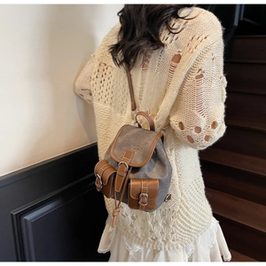 Detailed view of retro grey canvas backpack with brown leather trim worn by model