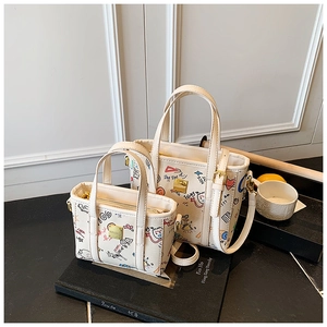 Detail of white graffiti printed bucket bags in two sizes with metallic hardware accent