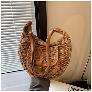 Detail of hand-woven straw crossbody bag with brown leather strap and front pocket