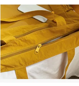 Close-up of yellow waterproof nylon tote bag with smooth matching resin zipper and metal pull