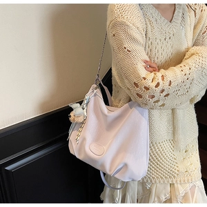 Detail of light purple tote bag with plush bear charm and fashion label displayed on shoulder