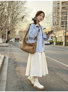 Outdoor shot of khaki canvas crossbody messenger bag showing the adjustable wide strap