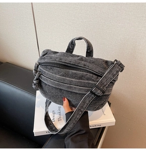 Detail of washed grey denim shoulder bag with adjustable strap and vintage texture