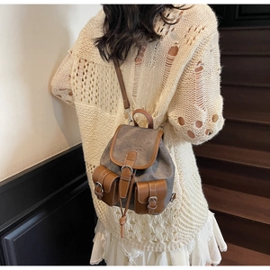 Detailed view of a vintage canvas backpack featuring brown leather trim and twin front pockets
