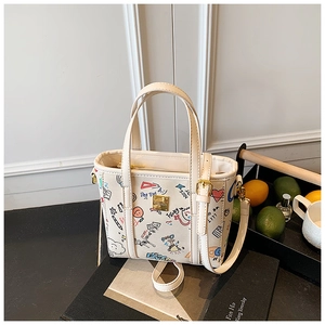 Detailed shot of cream crossbody bucket bag featuring colorful graffiti prints and gold hardware