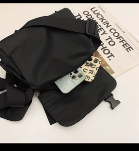 Detail of a black nylon messenger bag showing open flap and durable buckle closure