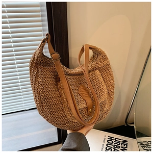 Detail of woven straw shoulder bag featuring a brown leather strap and metal buckle