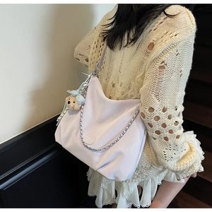 Detail of light purple hobo tote with silver chain and cute bear charm worn by a model