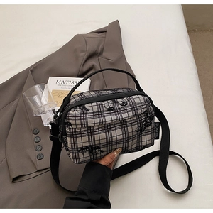 Detail shot of black and white tartan square bag with cute cat embroidery and side logo tag
