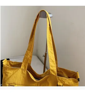 Detail of sturdy nylon handle and zipper pocket on a large yellow commuter tote bag