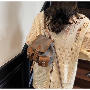 Close-up of vintage grey canvas backpack with brown leather trim on a model
