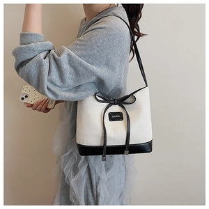 Detail of a chic black and white contrast shoulder bag with a delicate bow and metal tag