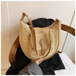 Detailed texture of beige woven straw hobo bag with brown leather strap on blazer