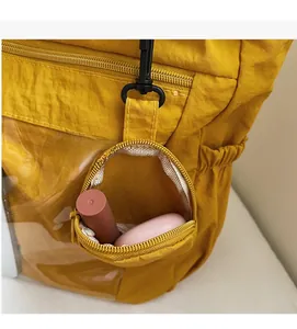 Detail of yellow nylon tote with a detachable round purse and transparent PVC pocket detail