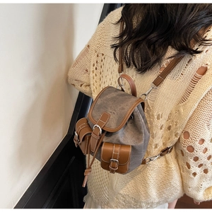 Detail view of retro canvas backpack with leather trim and decorative stitching worn by model