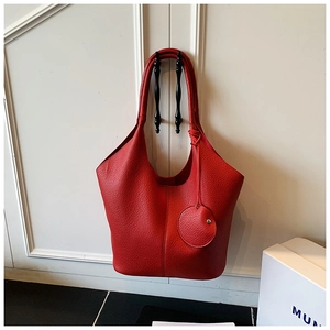 Detail of red lychee grain leather tote bag with side pouch and drawstring texture