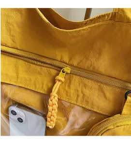Detail of smooth yellow nylon tote zipper and transparent PVC side pocket with phone
