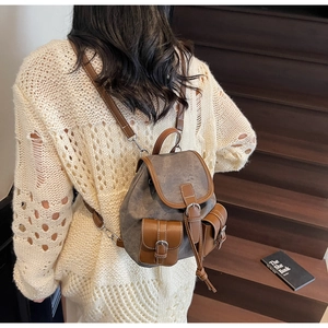 Detail of retro plaid backpack with brown leather trim and white contrast stitching