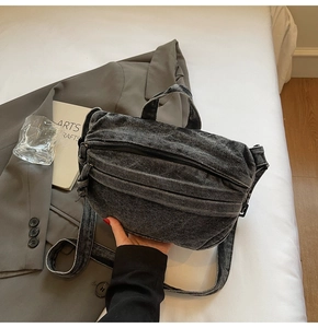Detail of charcoal denim crossbody bag with pleated texture and adjustable strap