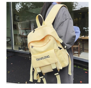 Detail of light yellow backpack showing front buckle strap and TIANFLONG embroidery logo