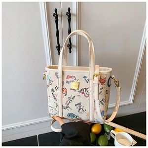 Detail showing the graffiti print handbag with gold hardware and top handle strap