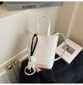 Détail du mini sac seau en cuir blanc avec charm floral décoratif et bandoulière