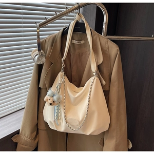 Detail of cream tote bag with soft pleated texture and a cute teddy bear charm