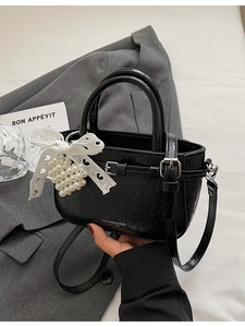 Schicke schwarze Plissee-Eimertasche mit Perlen-Spitzenanhänger auf grauem Blazer