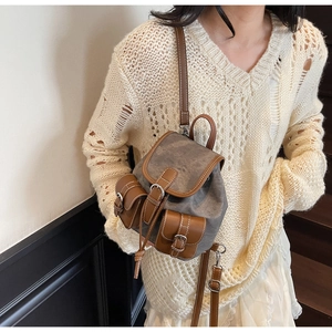 Retro grey canvas and brown leather mini backpack shown on a model's shoulder