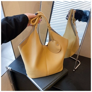 Detail view of yellow lychee pattern leather tote bag with round hanging ornament detail