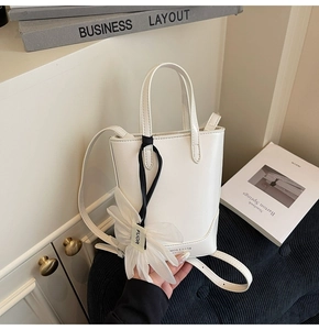 Détail du sac en cuir PU blanc avec un pendentif fleur en tissu blanc délicat