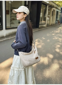 Detail of water-resistant nylon shoulder bag with adjustable strap and leather logo patch