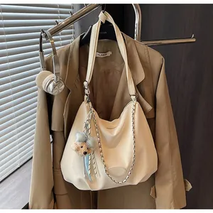 Chic cream tote bag with silver chain and cute bear charm in a lifestyle setting