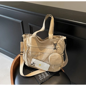 Close-up of beige nylon tote bag featuring front PVC zipper pocket and side mesh pocket