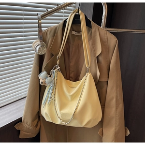 Detail of cream yellow leather hobo tote bag with silver chain and cute bear charm