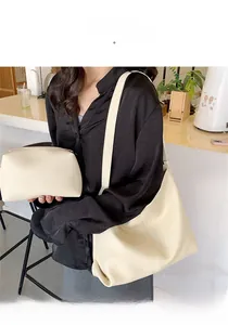Minimalist beige pebble leather tote bag with matching pouch shown on a model