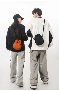 Sacs à bandoulière imperméables orange et noirs portés par des modèles pour l'extérieur