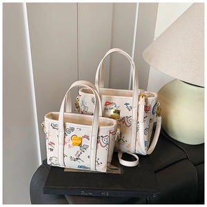 Close-up of cream graffiti-style handbag set with artistic hand-drawn patterns and gold hardware