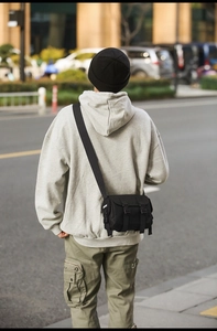 Close-up of a black techwear messenger bag featuring durable nylon fabric and buckle closures