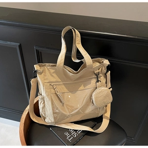 Detail of khaki nylon tote bag featuring transparent front pocket and round coin purse