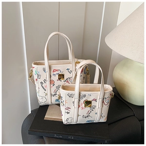 Detail view of two white tote bags with colorful graffiti prints and gold hardware