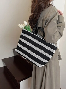 Grand sac cabas en maille rayée avec anses en cuir noir porté par un mannequin en intérieur