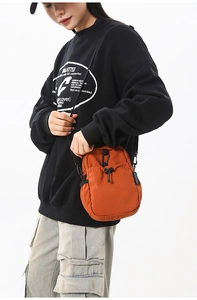 Détail du sac bandoulière en nylon orange avec cordon de serrage et mousqueton noir