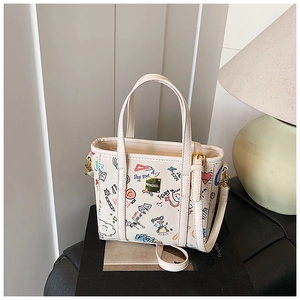 Detail of white graffiti tote bag with colorful hand-drawn prints and gold metal hardware