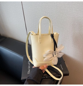 Vue détaillée du sac seau crème avec pendentif fleur en tissu et bandoulière réglable