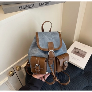 Detail view of retro blue denim mini backpack with brown leather trim and metal buckles