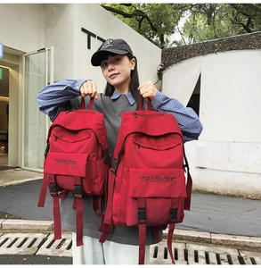 Detailed comparison of red canvas backpacks in large and small sizes with buckle closures
